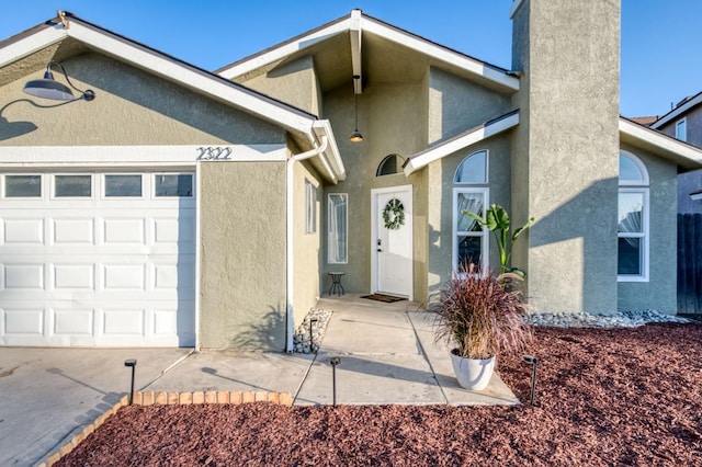 property entrance featuring a garage, driveway, and stucco siding