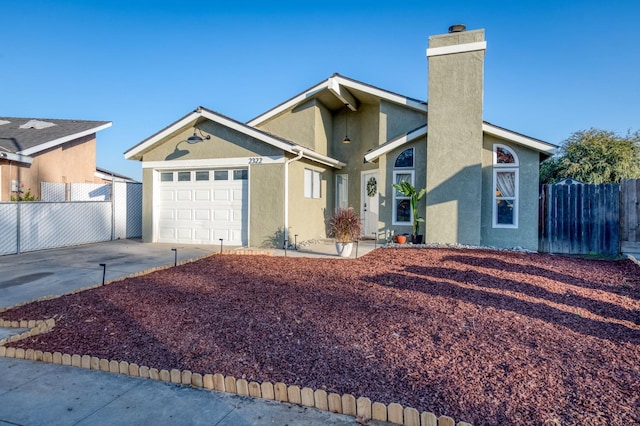 view of front of house featuring a garage, driveway, fence, and stucco siding