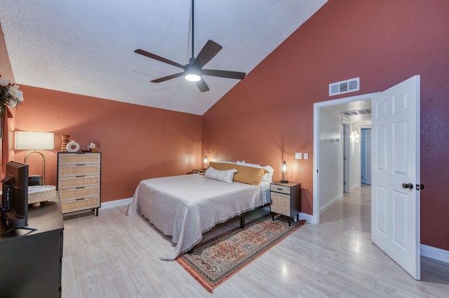 bedroom with baseboards, high vaulted ceiling, visible vents, and light wood-style floors