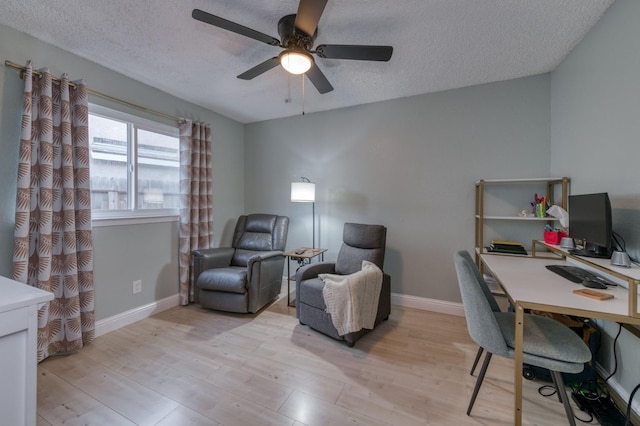 office space featuring light wood-style floors, a ceiling fan, baseboards, and a textured ceiling