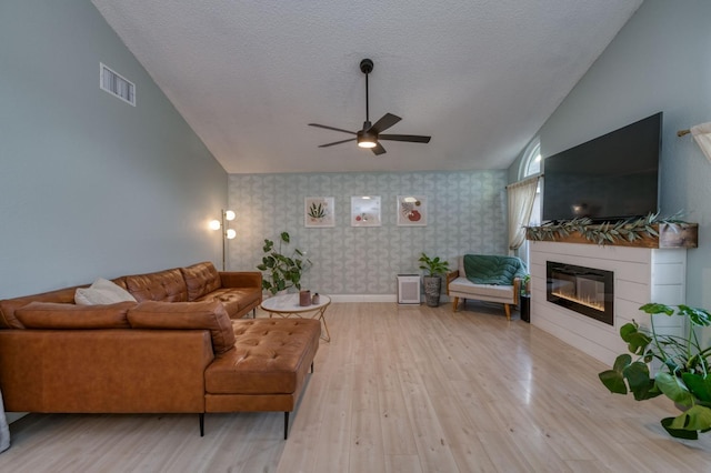 living room featuring wallpapered walls, visible vents, vaulted ceiling, and wood finished floors