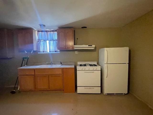 683 E Polk St, Coalinga, CA 93210 - kitchen with brown cabinetry, white appliances, light countertops, under cabinet range hood, and a sink