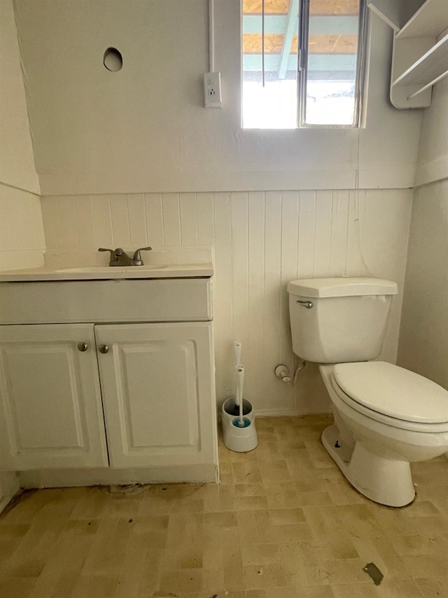 half bath featuring toilet, vanity, and wainscoting