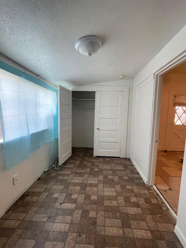 unfurnished bedroom with brick floor, a textured ceiling, and a closet