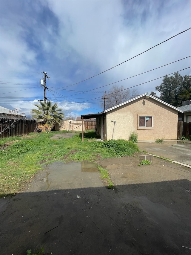 view of side of property featuring fence and stucco siding