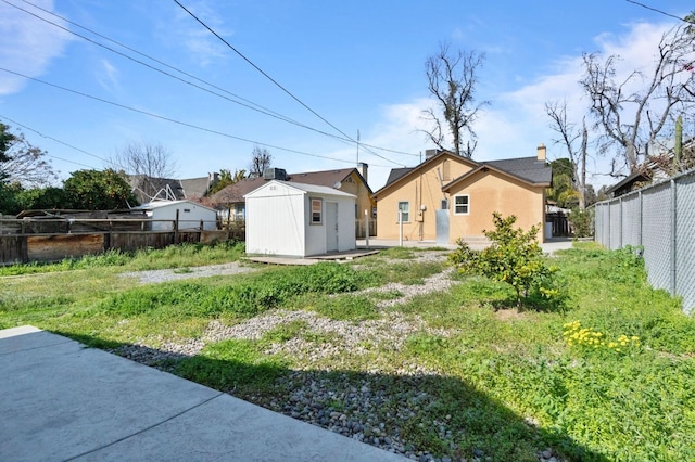 view of yard with a shed, fence, and an outbuilding