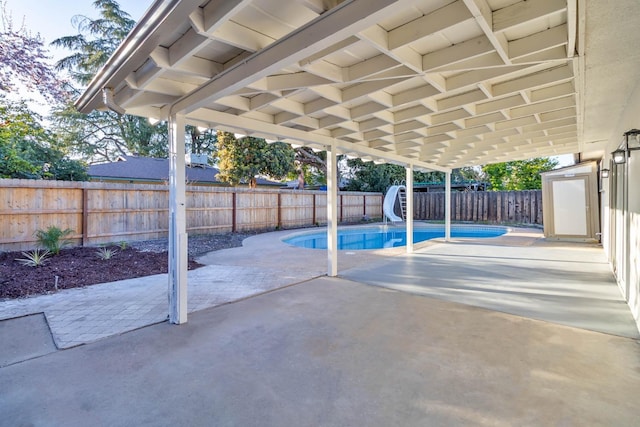 view of swimming pool featuring a patio, a water slide, a fenced backyard, and a fenced in pool