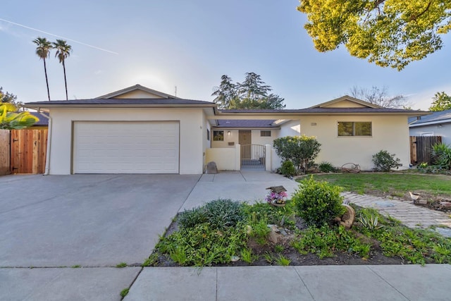 ranch-style home featuring an attached garage, fence, and stucco siding