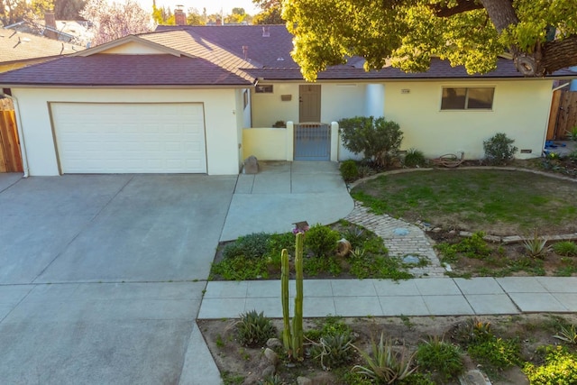 single story home with a gate, fence, concrete driveway, and stucco siding