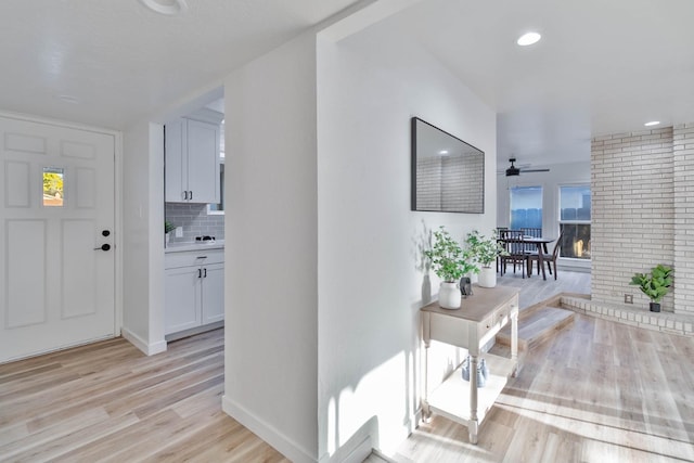 corridor with light wood-style floors, recessed lighting, and baseboards