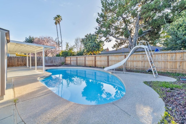 view of pool with a fenced in pool, a water slide, a patio area, and a fenced backyard