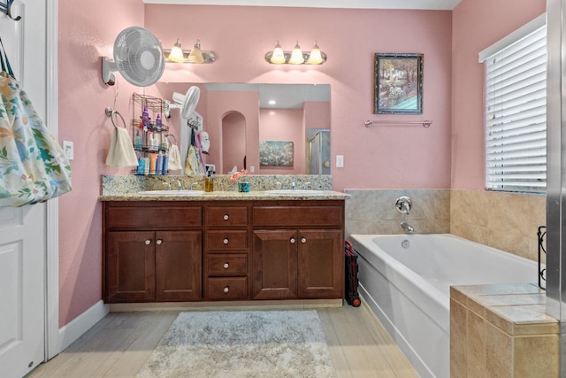 bathroom with a garden tub, double vanity, a sink, and a shower stall