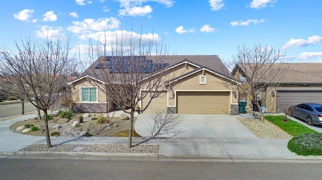 view of front of property featuring a garage, concrete driveway, stone siding, roof mounted solar panels, and stucco siding