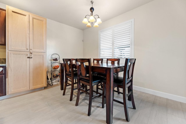 dining room with baseboards, a chandelier, and light wood-style flooring