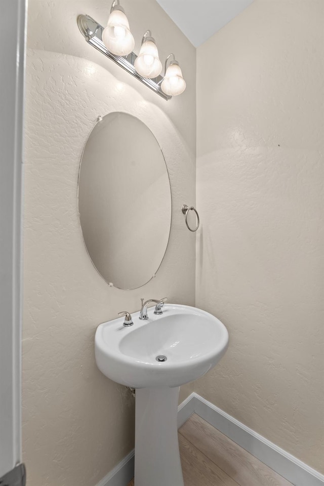 bathroom with a textured wall, wood finished floors, and baseboards