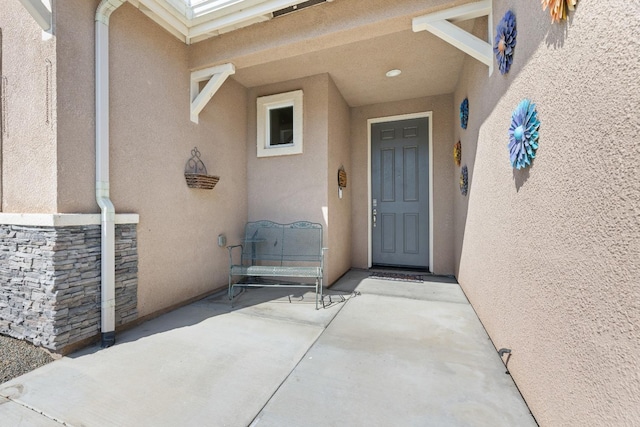 property entrance featuring stone siding and stucco siding