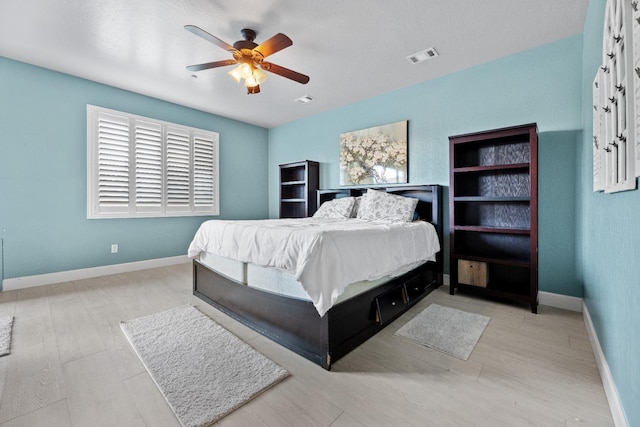 bedroom with ceiling fan, wood finished floors, visible vents, and baseboards