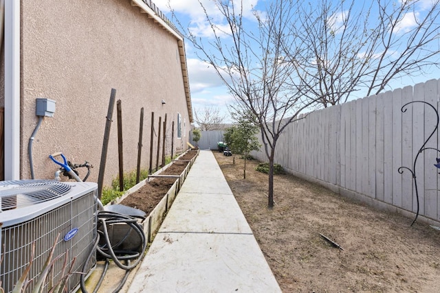 view of yard featuring central AC unit, a fenced backyard, and a garden