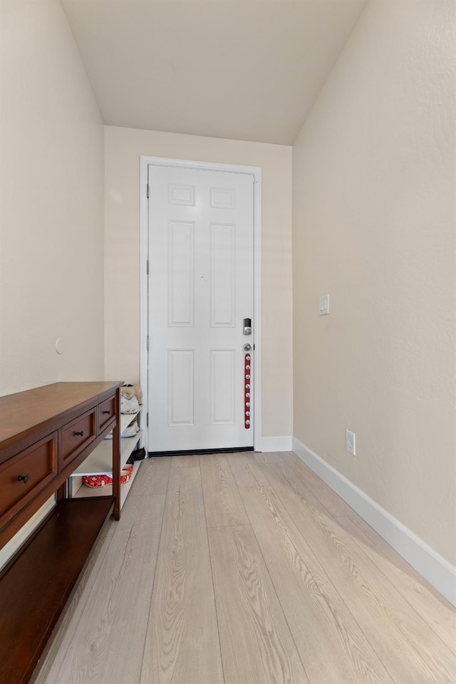 entrance foyer featuring lofted ceiling, light wood-style flooring, and baseboards