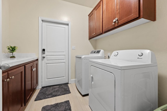 laundry area featuring light wood-style flooring, cabinet space, and washer and clothes dryer