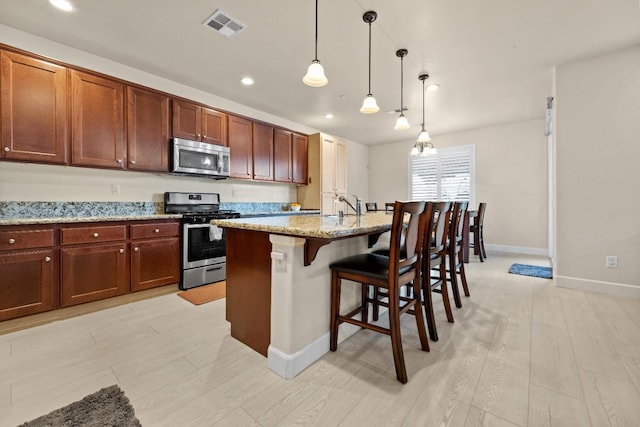 kitchen with appliances with stainless steel finishes, a breakfast bar, visible vents, and light wood-style floors