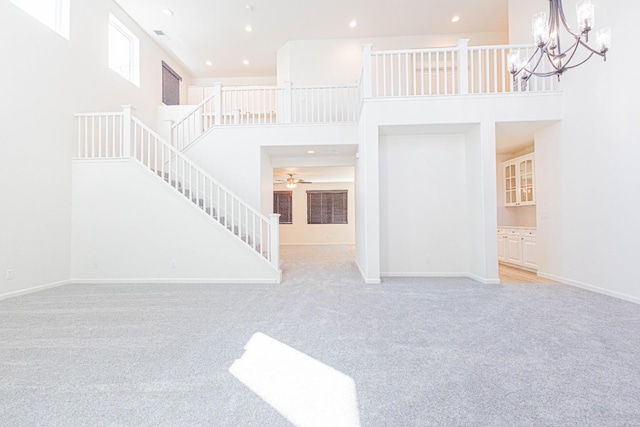 unfurnished living room with baseboards, a high ceiling, carpet floors, and stairs