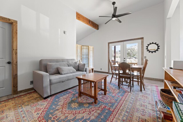 living area featuring lofted ceiling with beams, light wood-style flooring, a ceiling fan, baseboards, and french doors