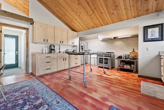 kitchen featuring lofted ceiling, light brown cabinetry, appliances with stainless steel finishes, wood ceiling, and wall chimney exhaust hood