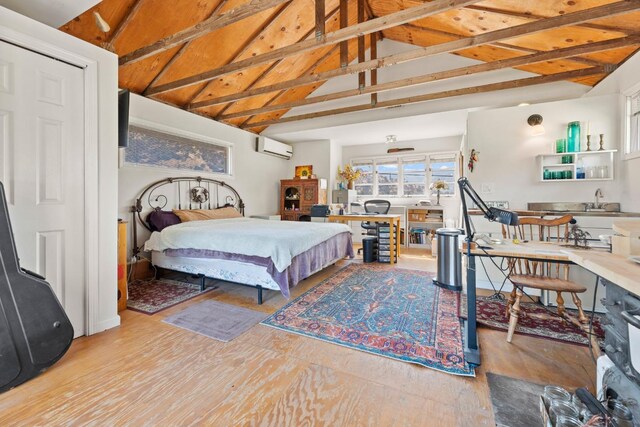 bedroom featuring vaulted ceiling, a wall unit AC, and wood finished floors