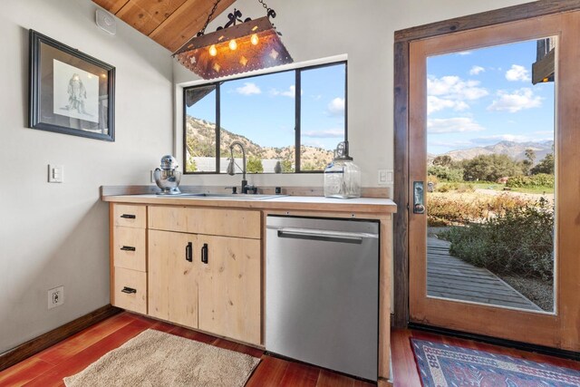 kitchen with wood finished floors, stainless steel dishwasher, light brown cabinets, a mountain view, and a sink