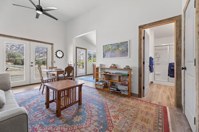 living room featuring light wood-style floors, high vaulted ceiling, a ceiling fan, and french doors