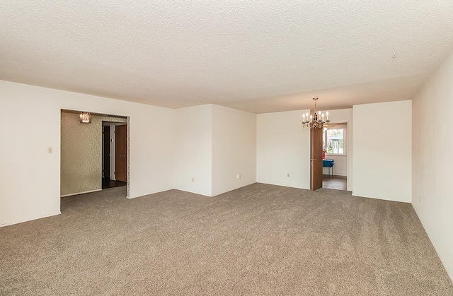 empty room featuring a textured ceiling, a notable chandelier, and carpet flooring