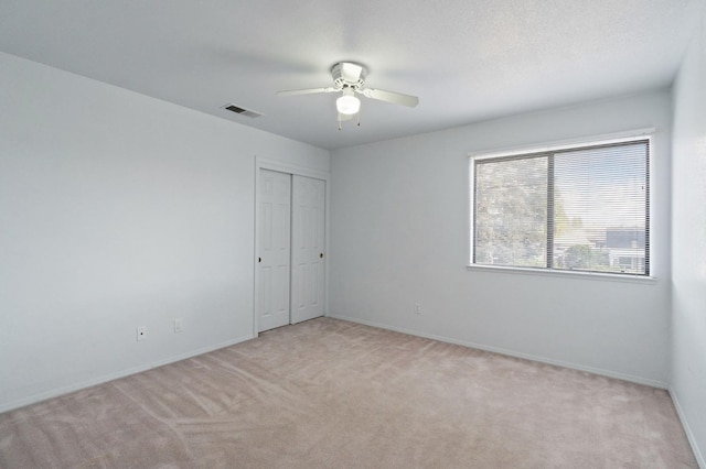 unfurnished room with visible vents, baseboards, a ceiling fan, and light colored carpet