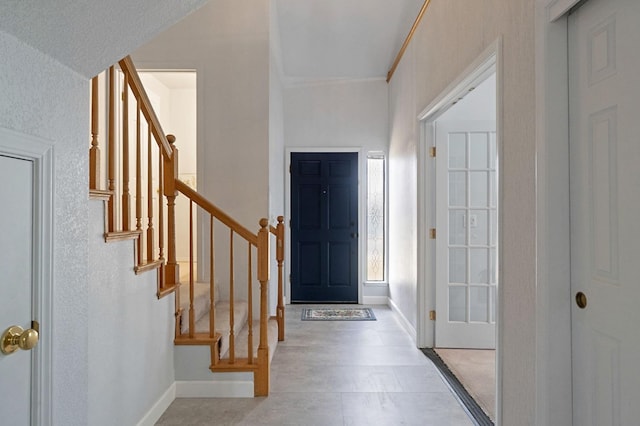 entrance foyer with stairs, baseboards, and ornamental molding