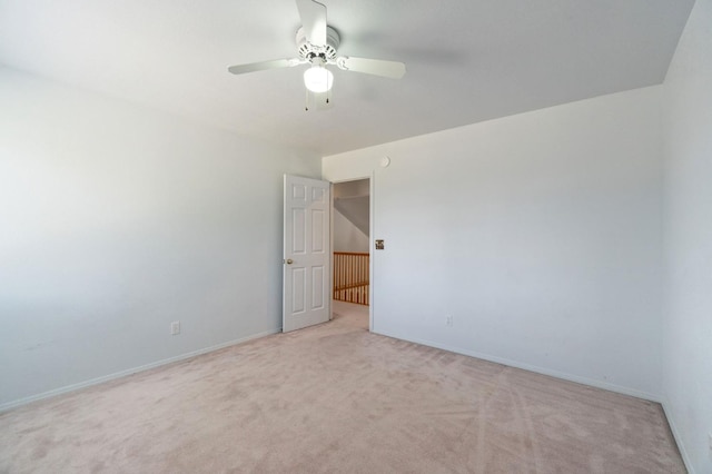 unfurnished room with a ceiling fan, light carpet, and baseboards