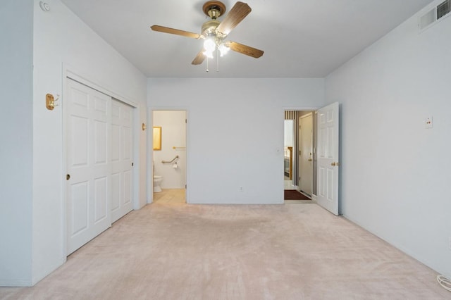 unfurnished bedroom featuring a closet, visible vents, carpet flooring, connected bathroom, and ceiling fan