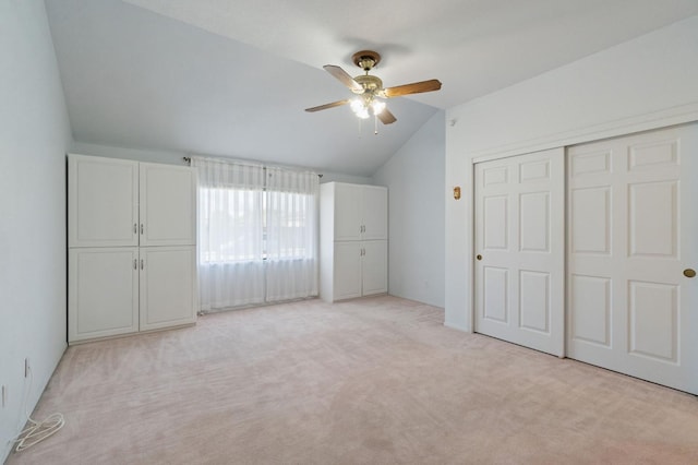 unfurnished bedroom featuring lofted ceiling, a closet, light colored carpet, and ceiling fan