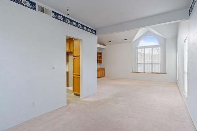 spare room featuring light carpet and vaulted ceiling