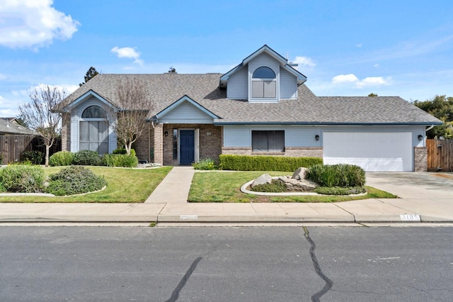 view of front facade with brick siding, roof with shingles, concrete driveway, fence, and a garage