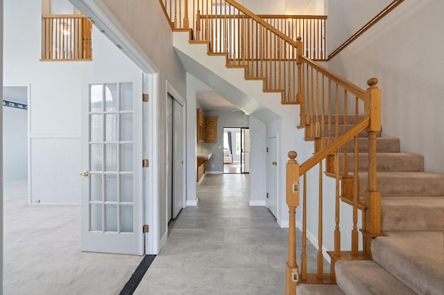 stairway featuring a high ceiling and baseboards