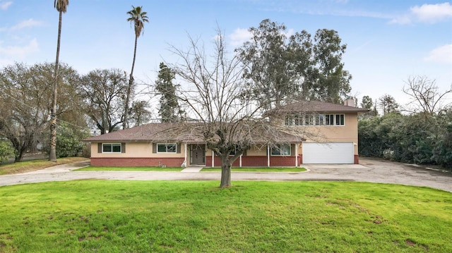 view of front of house with brick siding, a chimney, stucco siding, driveway, and a front lawn