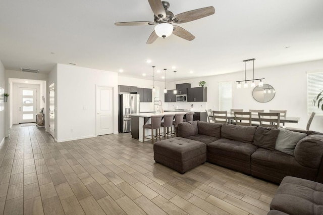 living room with recessed lighting, visible vents, ceiling fan, and light wood-style flooring