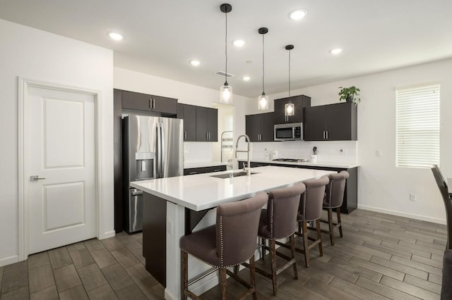 kitchen with appliances with stainless steel finishes, wood finish floors, light countertops, and a sink