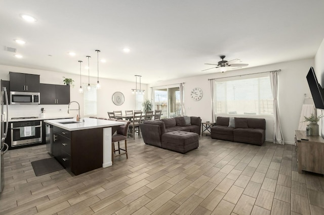 kitchen featuring a breakfast bar area, visible vents, open floor plan, light countertops, and appliances with stainless steel finishes