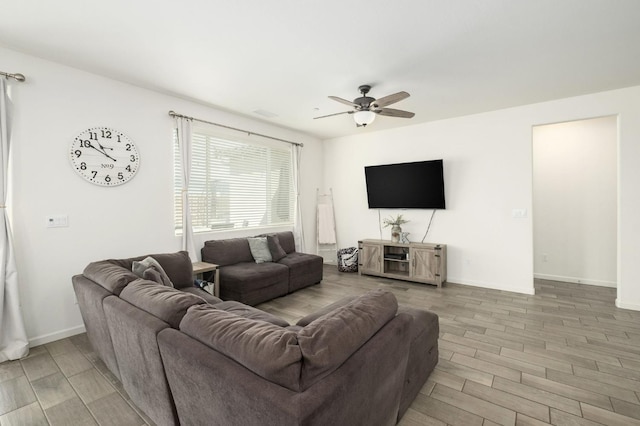 living area with a ceiling fan, wood finish floors, and baseboards