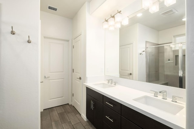 bathroom featuring wood tiled floor, visible vents, a sink, and a shower stall