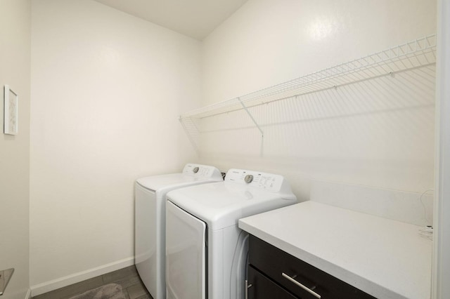 clothes washing area with washing machine and dryer, laundry area, and baseboards