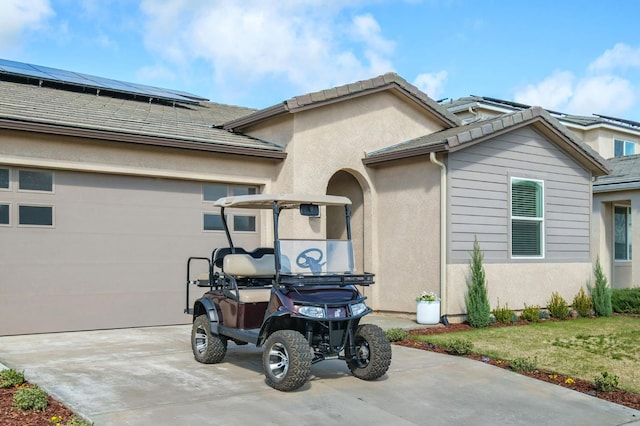 view of side of home with a garage, concrete driveway, a tiled roof, roof mounted solar panels, and stucco siding