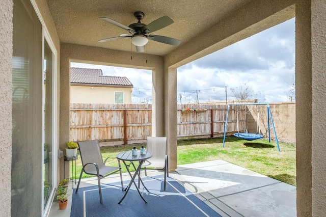 view of patio with a trampoline, a fenced backyard, and a ceiling fan