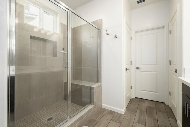 full bathroom with a stall shower, wood tiled floor, visible vents, and vanity